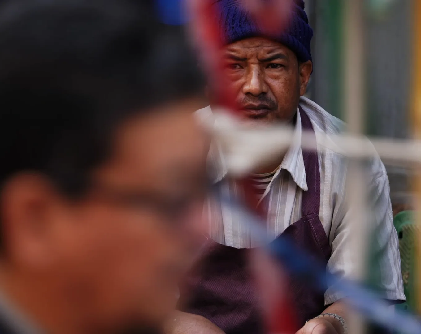 A Nepal street portrait seen through a blurred foreground