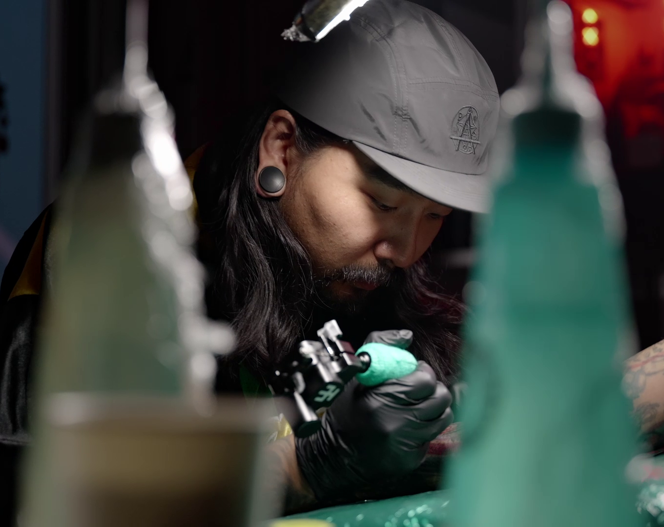 Tattoo artist working behind colored bottles