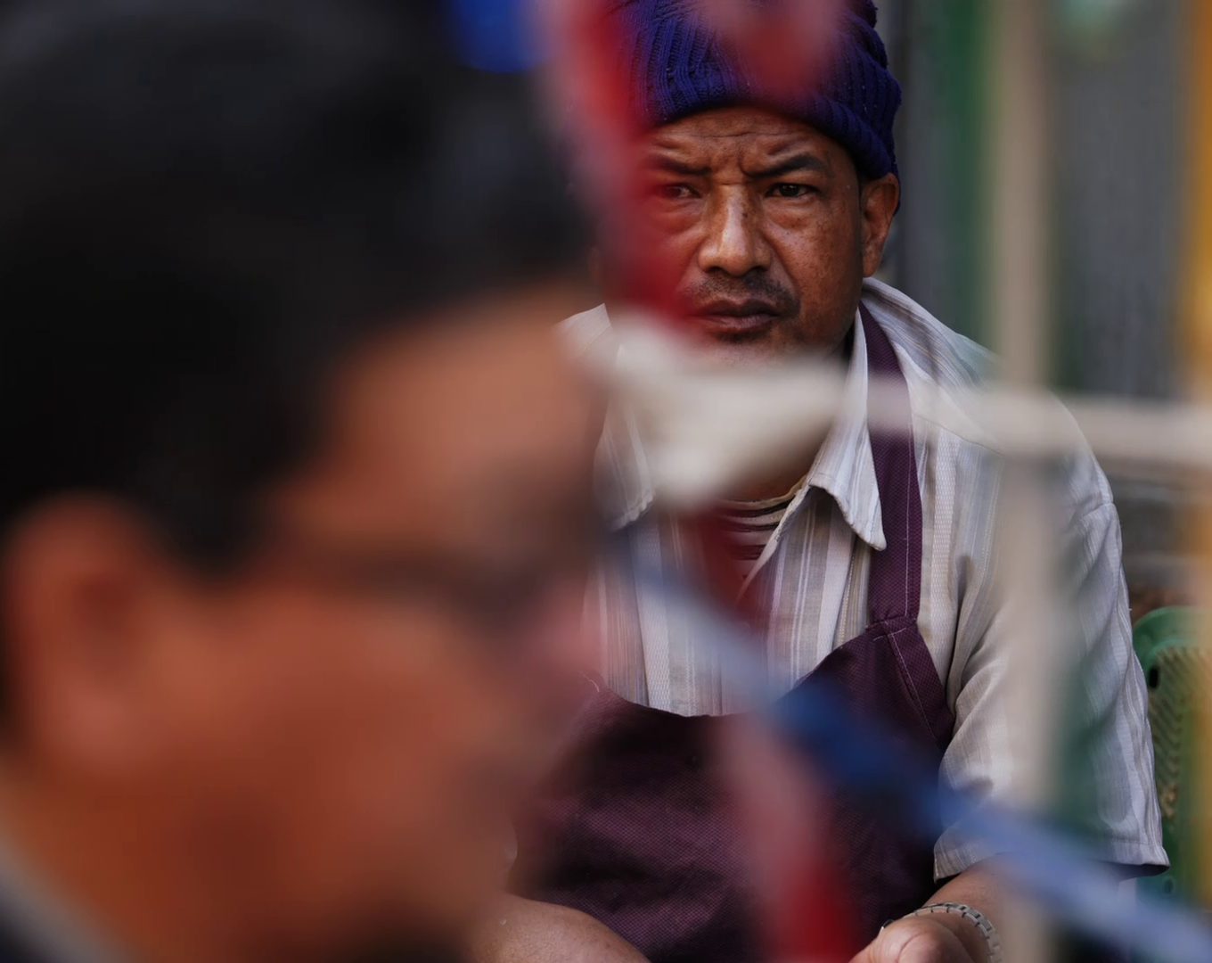 A Nepal street portrait seen through a blurred foreground